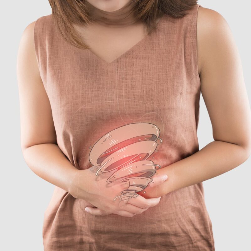 A woman holding her stomach with both hands, appearing to be in pain. A digital graphic of red, concentric rings over her abdomen highlights IBS symptoms or digestive discomfort, possibly requiring an IBS diet.