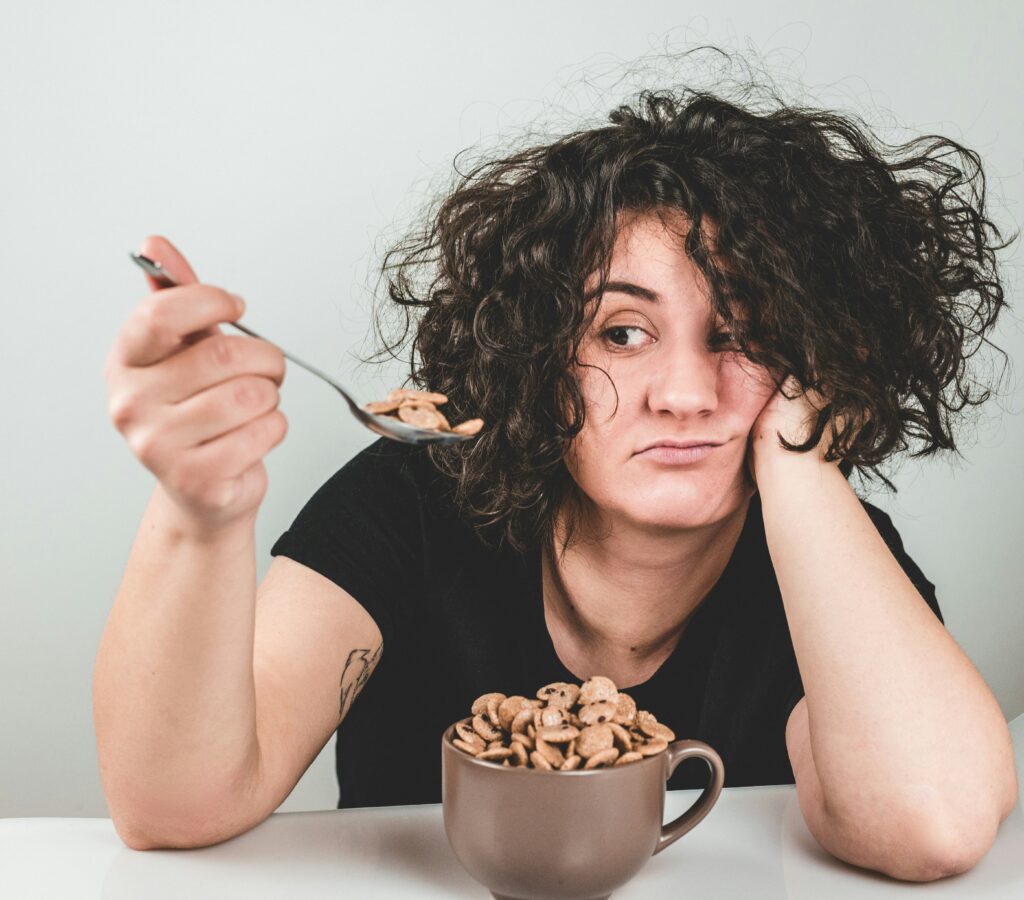 stressed woman looking at spoonful of sugary cereal