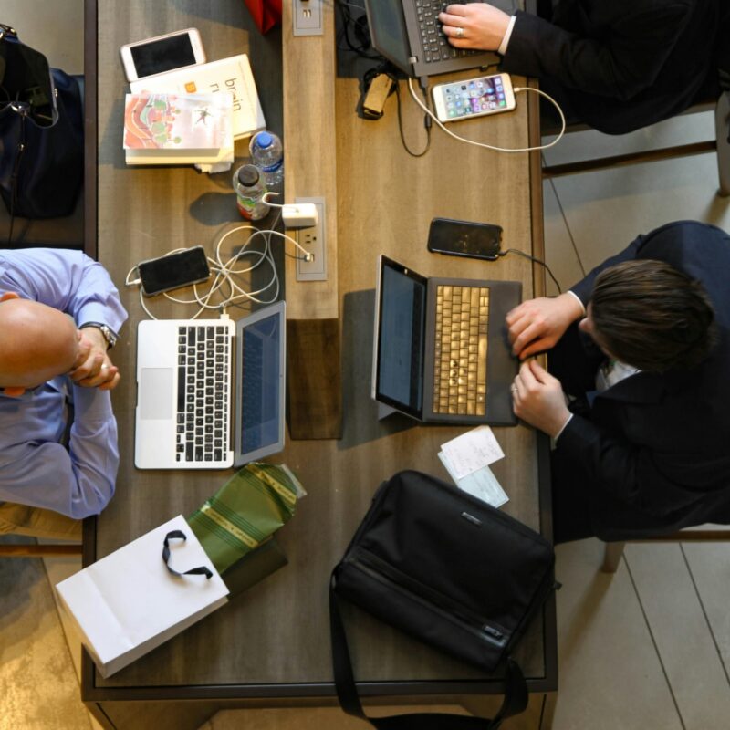 office workers sitting at communal desk with computers