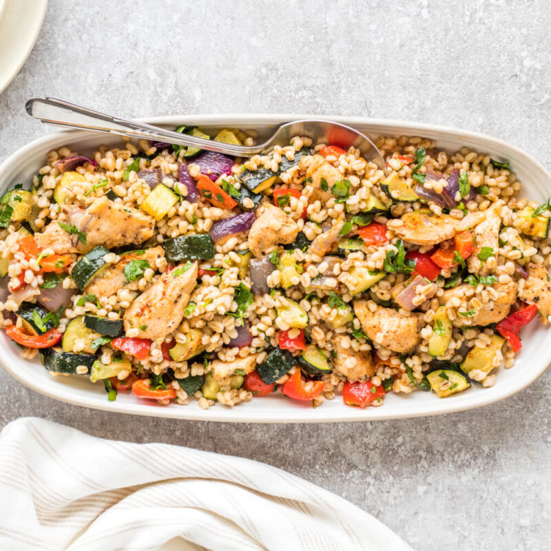 Harissa Chicken, Barley & Roasted Veggies in a serving tray on a table