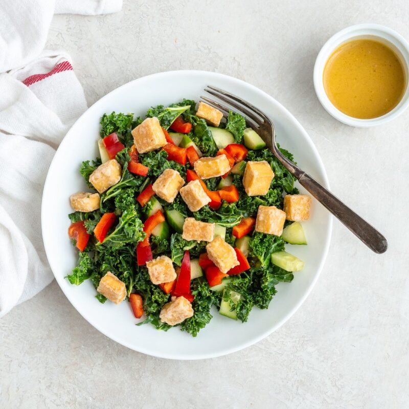 Maple mustard kale salad with crispy tofu on plate on a table