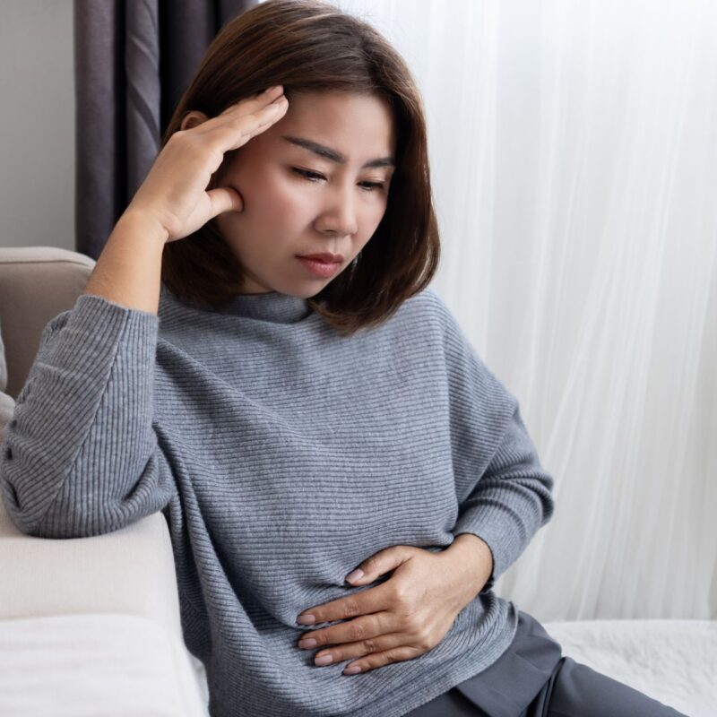A stressed out woman on a couch holding her gut