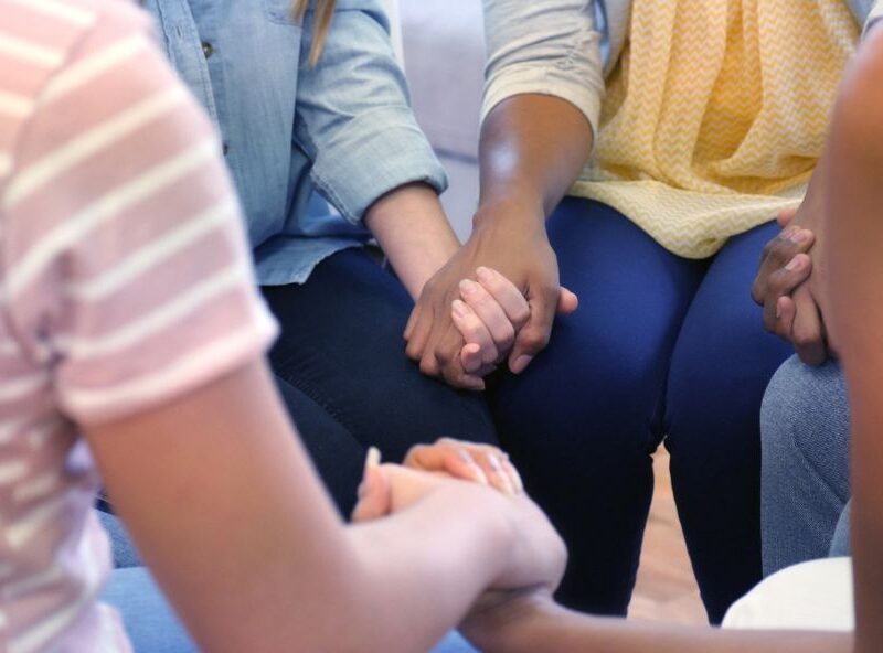 Women in a support group circle golding hands